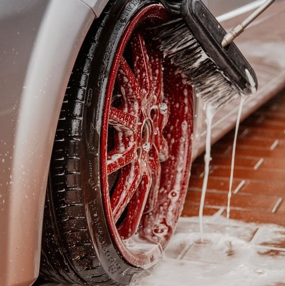 A close-up photo of a red car wheel being washed